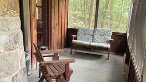 Eine Holzhütte mit einem karierten Tisch, einer Holzbank und einer gepolsterten Couch.