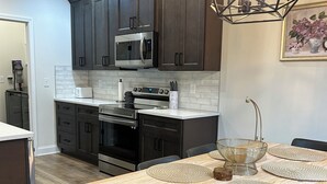 A modern kitchen with dark cabinets, a stainless steel microwave, and a wooden dining table with woven placemats. - Nice house in Tellico village close to lake and golf course  (Loudon)
