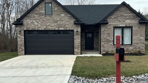 A two-story house with a brick facade, a dark roof, and a garage. - Nice house in Tellico village close to lake and golf course  (Loudon)