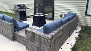 An outdoor patio with a grill, a table, and a wicker sofa with cushions. - Nice house in Tellico village close to lake and golf course  (Loudon)