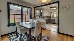 A dining area with a table and chairs, a large window, and a view of the outside. - NEW Old Southwest Gem, Patio, Grill, Smart TV, 2 Desks + Fitness Equipment

 (Reno)