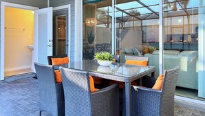 Un patio con una mesa de vidrio, sillas de mimbre y una planta en maceta.