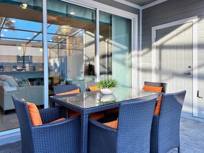 A glass-enclosed patio with wicker furniture and a potted plant.