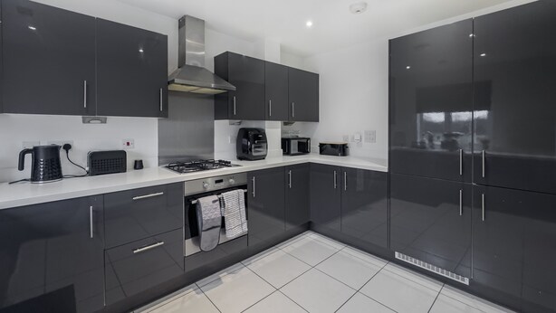 A modern kitchen with dark cabinets, a gas stove, a microwave, and a coffee maker.
