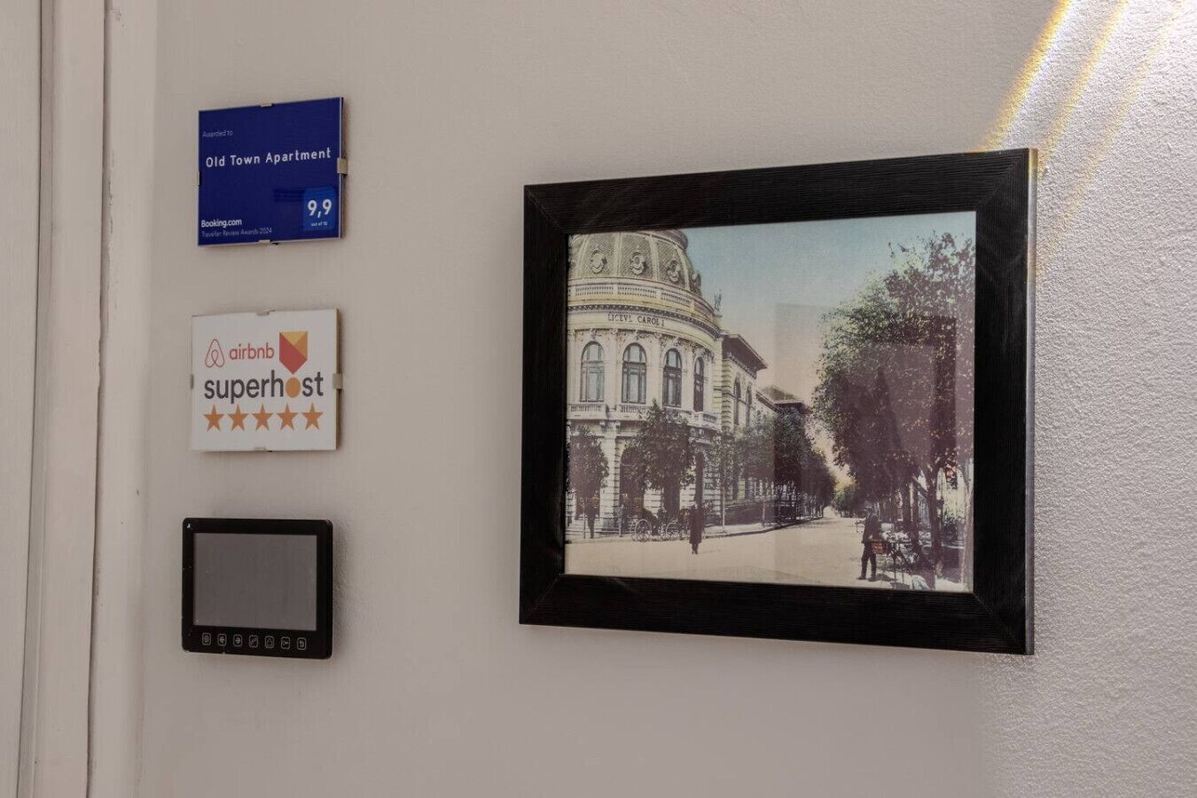 A wall with a framed historical photograph, a blue sign with a 9.9 rating, and an Airbnb superhost badge.