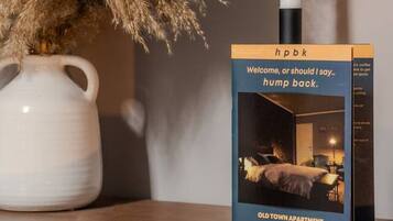 A candle, pampas grass, and a book titled 'hpbk' on a table.