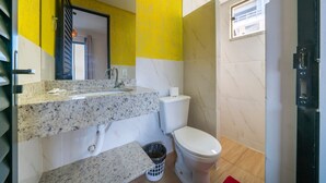 A bathroom with a marble sink, toilet, and a window.