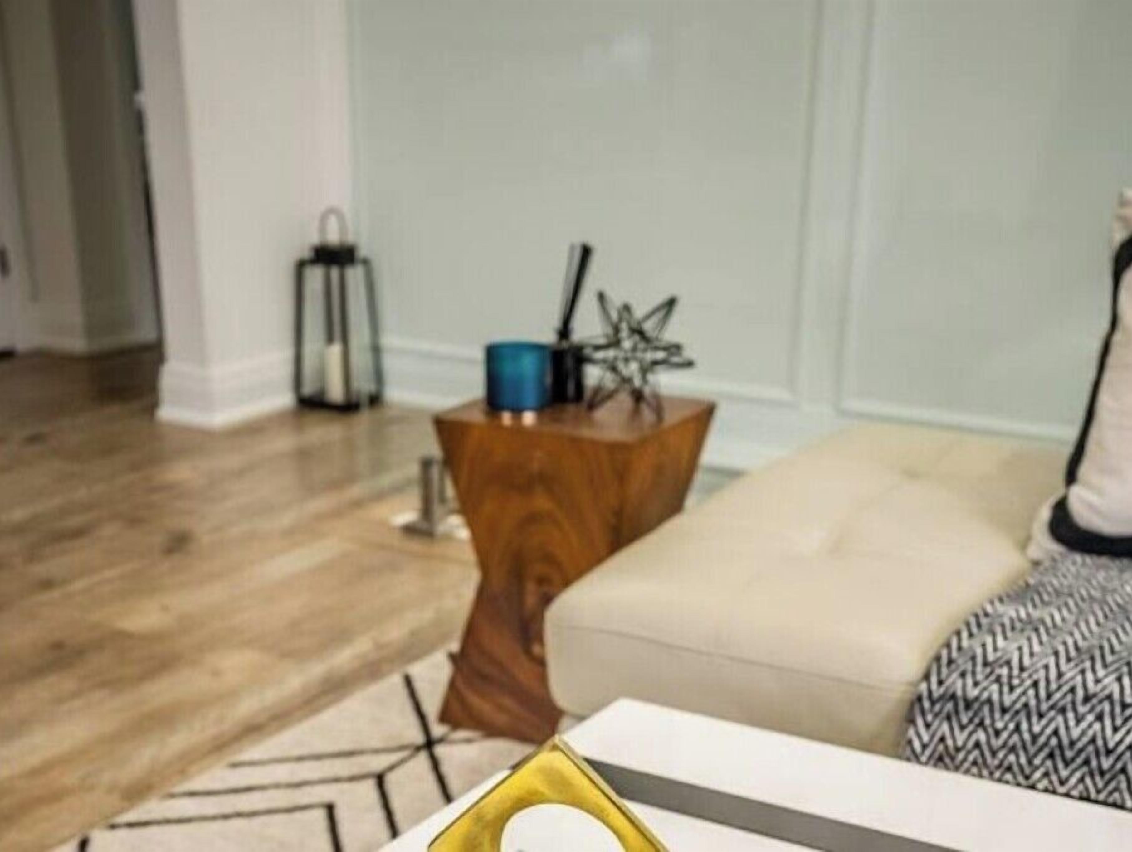 A living room with a wooden coffee table, a beige sofa, and a patterned throw pillow.