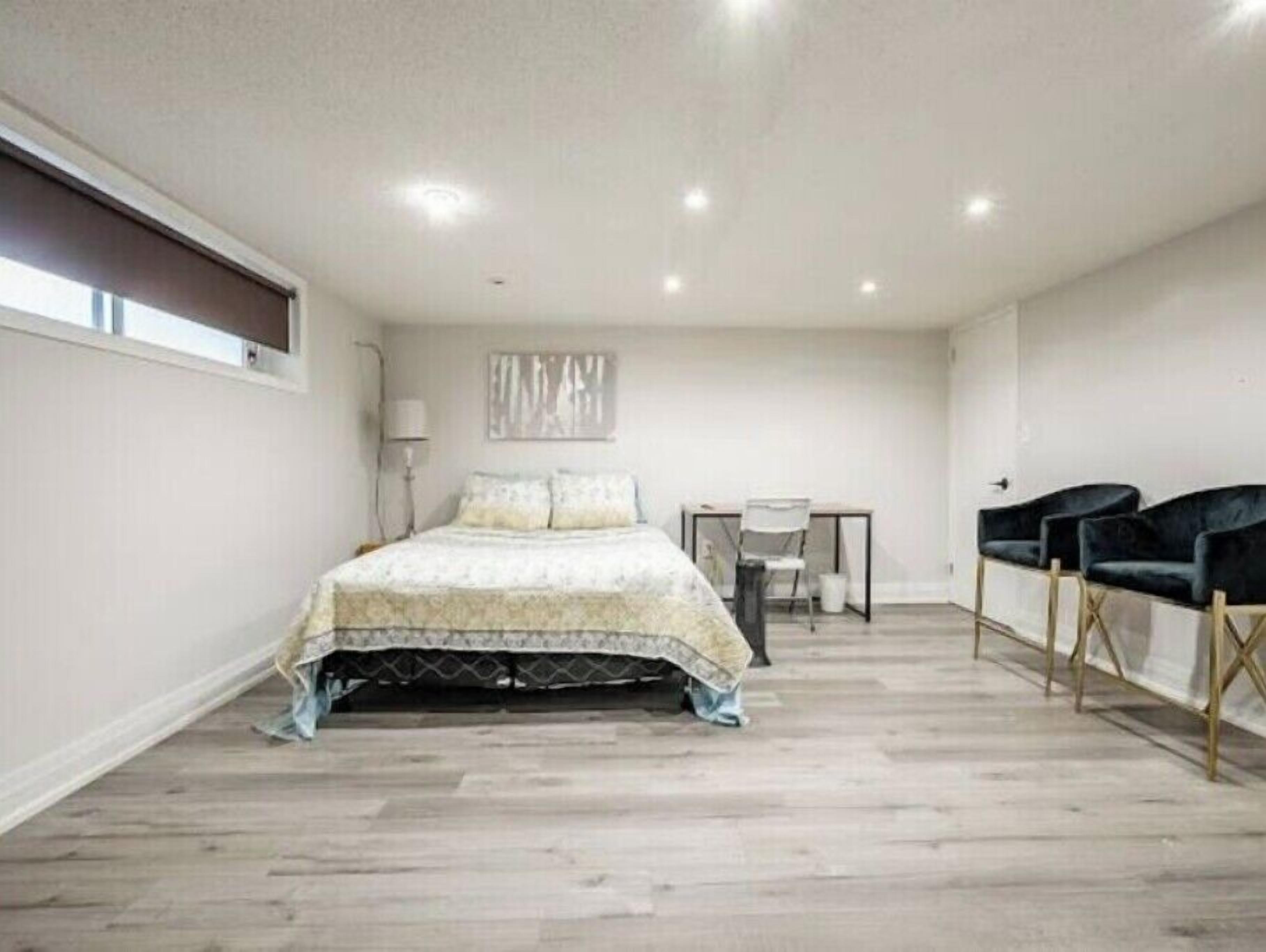 A bedroom with a bed, a desk, and two chairs.
