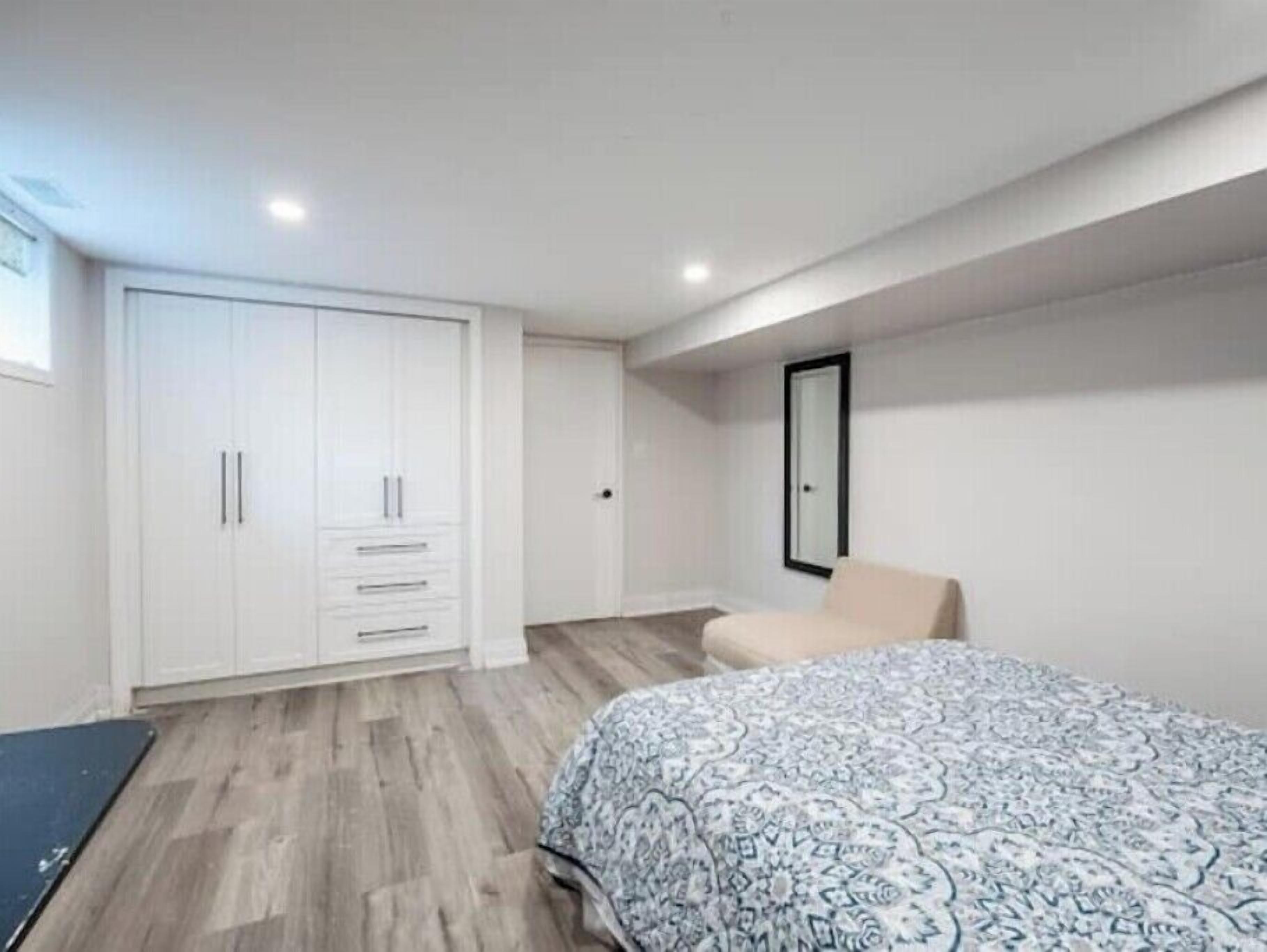 A bedroom with a bed, a wardrobe, and a chair.