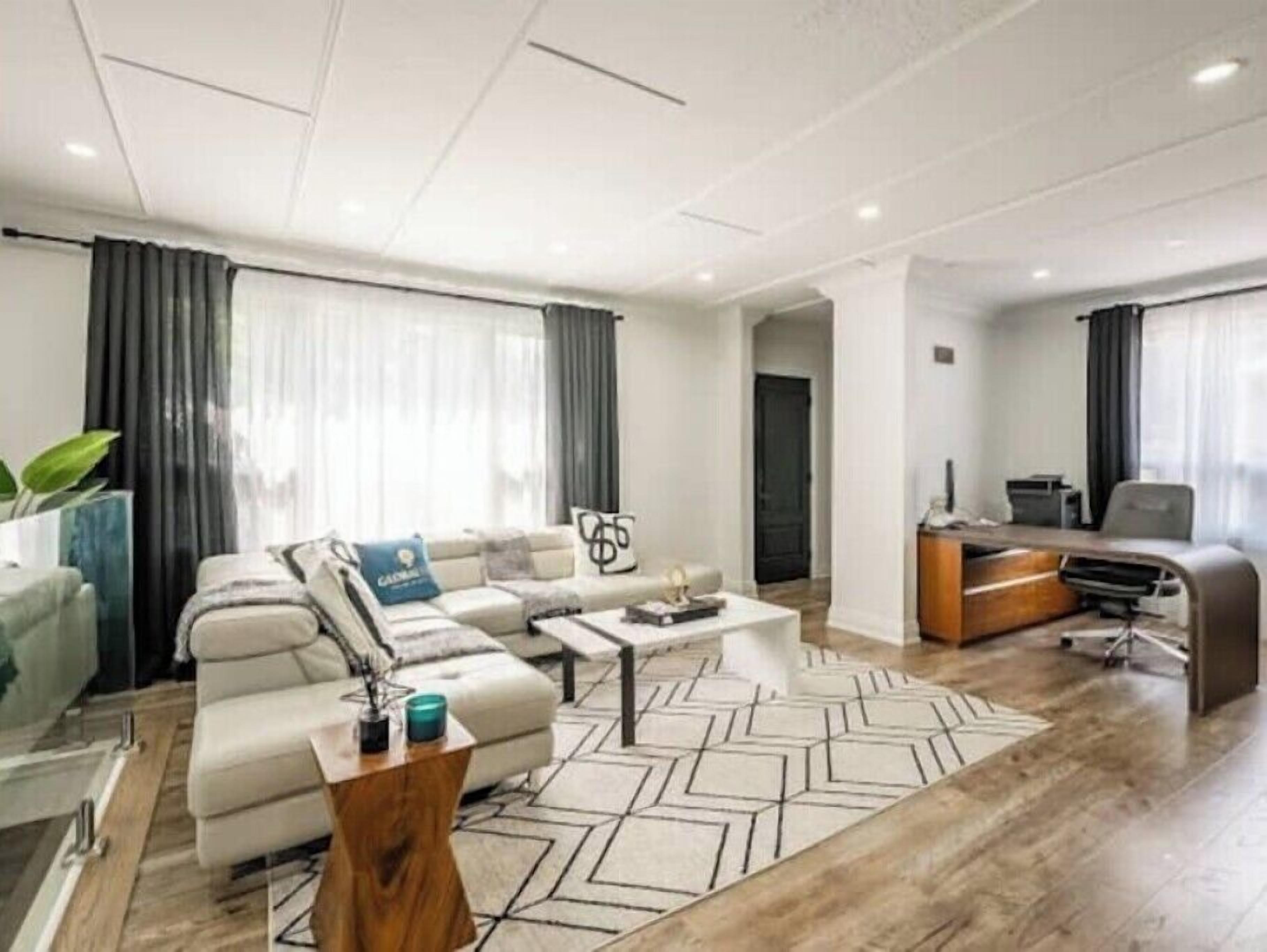 Een moderne woonkamer met een bank, salontafel en een werkhoek met een computer.