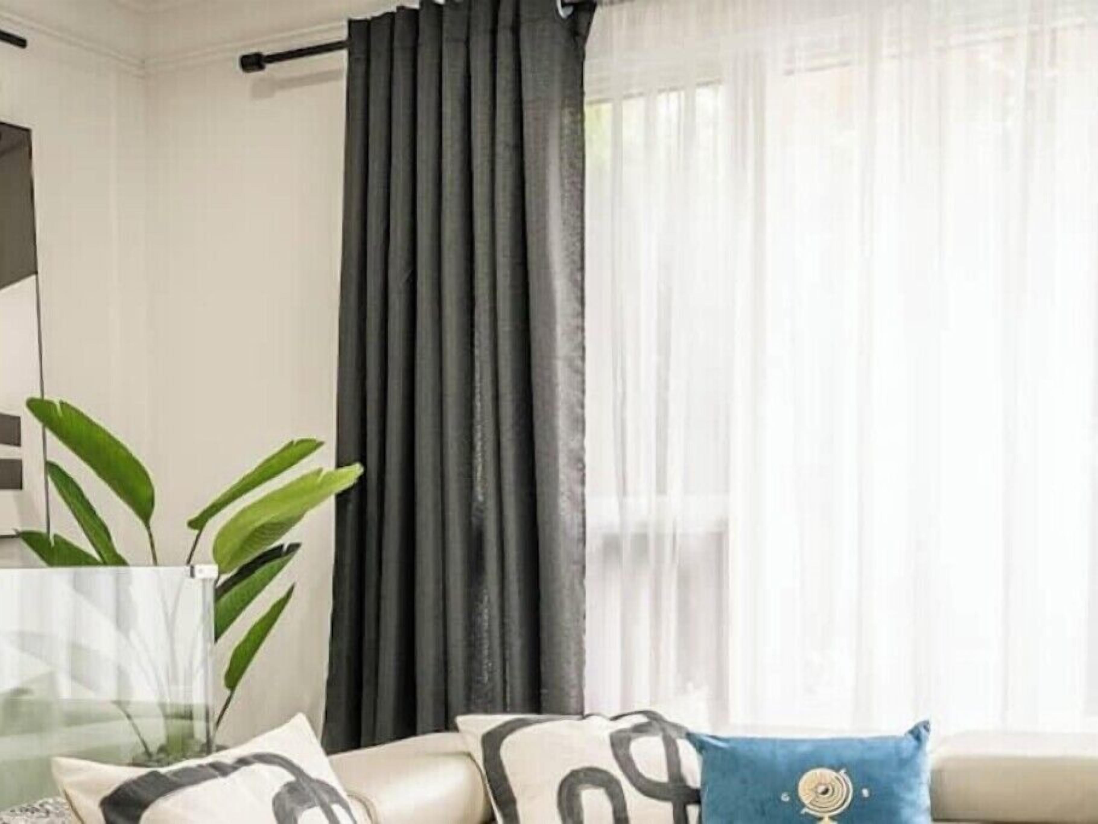 Een moderne woonkamer met een bank, een glazen vaas met een plant en een raam met gordijnen.