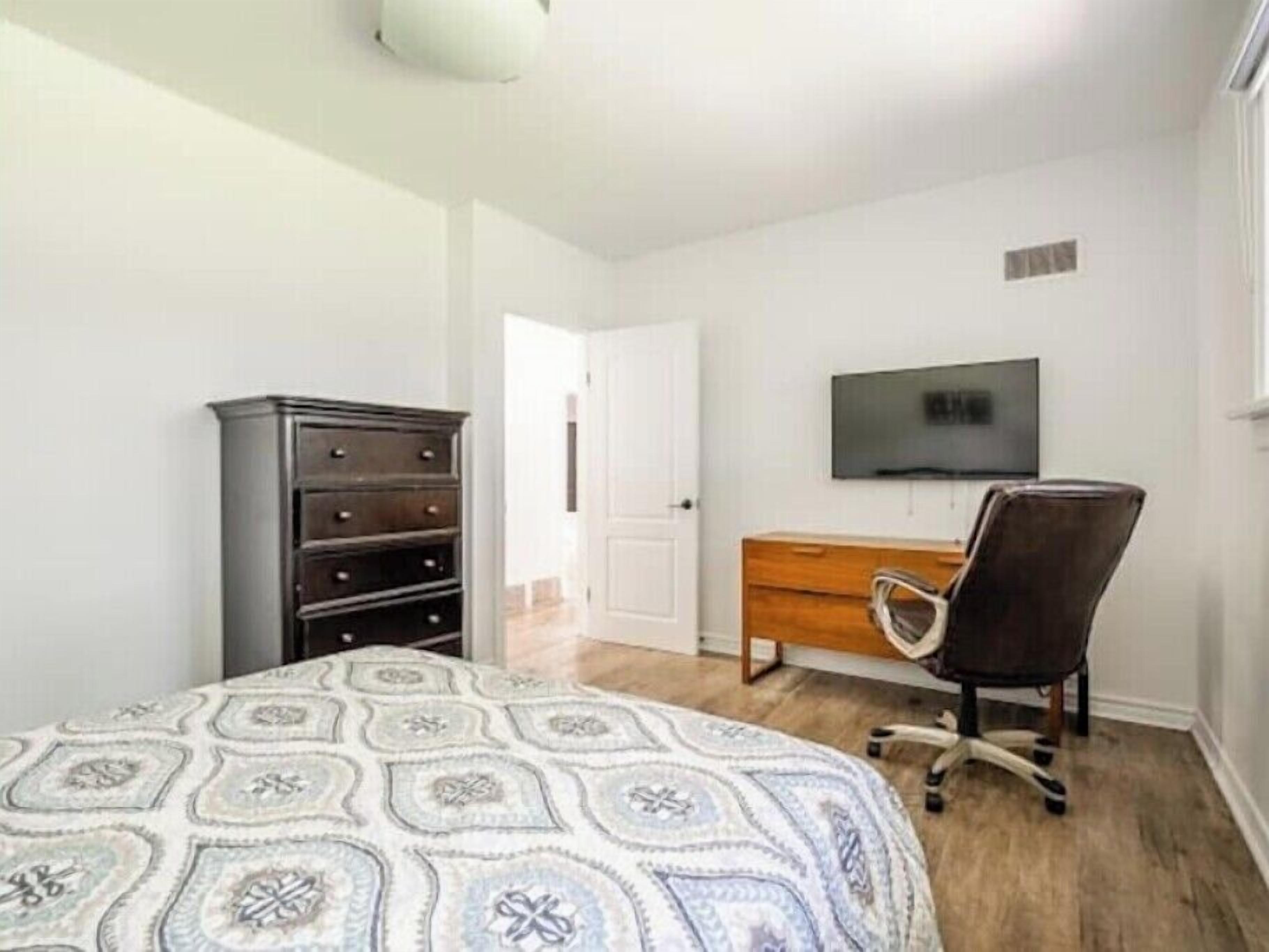 A bedroom with a bed, a dresser, a desk, and a chair.