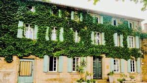 A building with multiple windows, some with shutters, covered in green ivy. - Ideal for friends: "La Belle Dame sans Regrets" with swimming pool, garden & workshop  (Talairan)