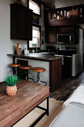 Una cocina moderna con armarios de madera oscura, encimera de granito, horno integrado y un ventanal grande.