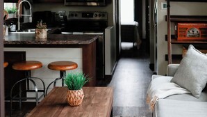 A cozy kitchen with a wooden table, bar stools, and a hanging light fixture.