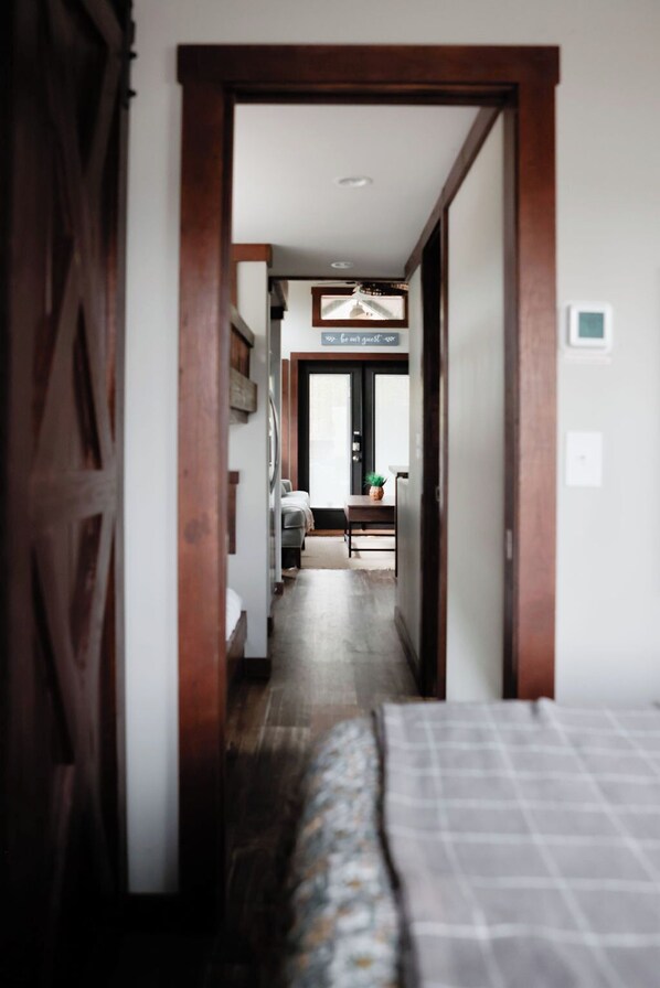 A narrow hallway leading to a room with a bed, a desk, and a chair. There is a sign above the door that reads "For our guest."