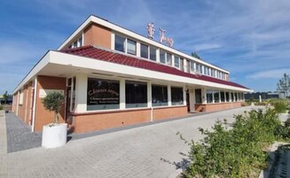 Un edificio de dos pisos con techo rojo y un cartel que dice 'Chamber of Commerce'.