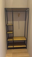 Una habitación con una estantería empotrada de madera con tres repisas y una lámpara colgante.