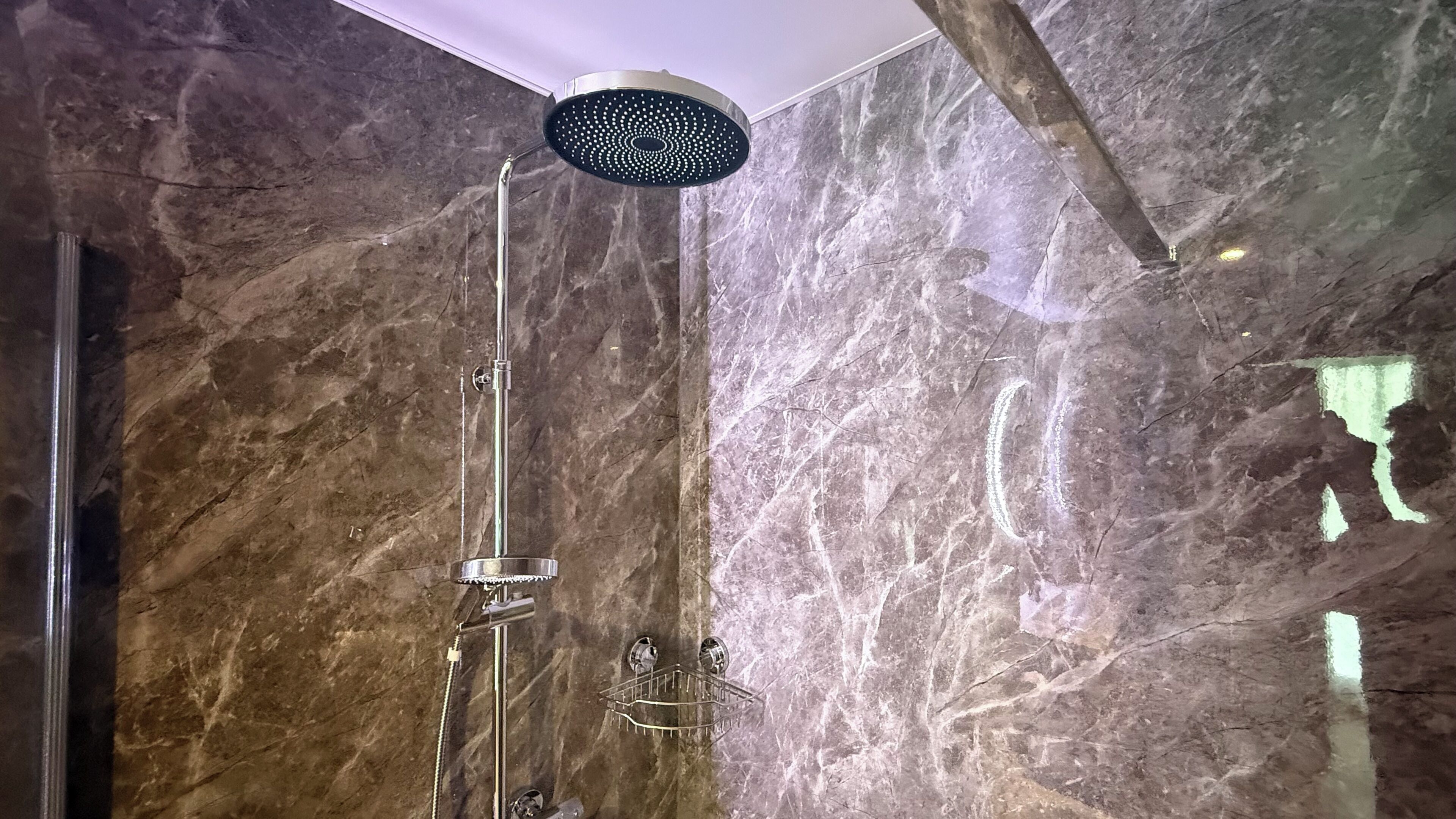 A shower with a rain showerhead, a handheld showerhead, and a handheld massage nozzle.