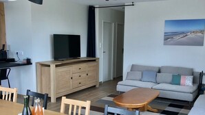 Un salon moderne comprenant un coin repas, un canapé, un téléviseur et un tableau accroché au mur.