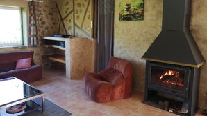 Ein Wohnzimmer mit Kamin, einem roten Sessel, einem Glastisch und einer Steinwand.