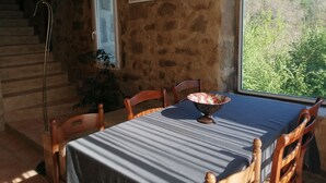 Ein Essbereich mit einem Tisch für vier Personen, einer Treppe, einem Wandbild und Blick auf einen Wald durch ein Fenster.