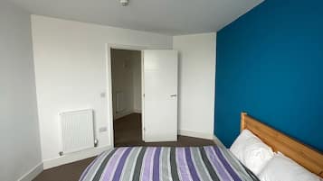 Une chambre à coucher avec un lit, un radiateur, une porte et un mur bleu.