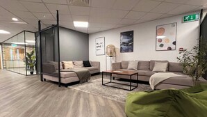 A modern office space with two sofas, a coffee table, and a green bean bag.