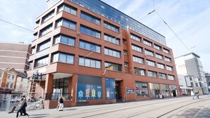 A multi-story building with a modern architectural design, featuring large windows and a mix of brick and glass facades.