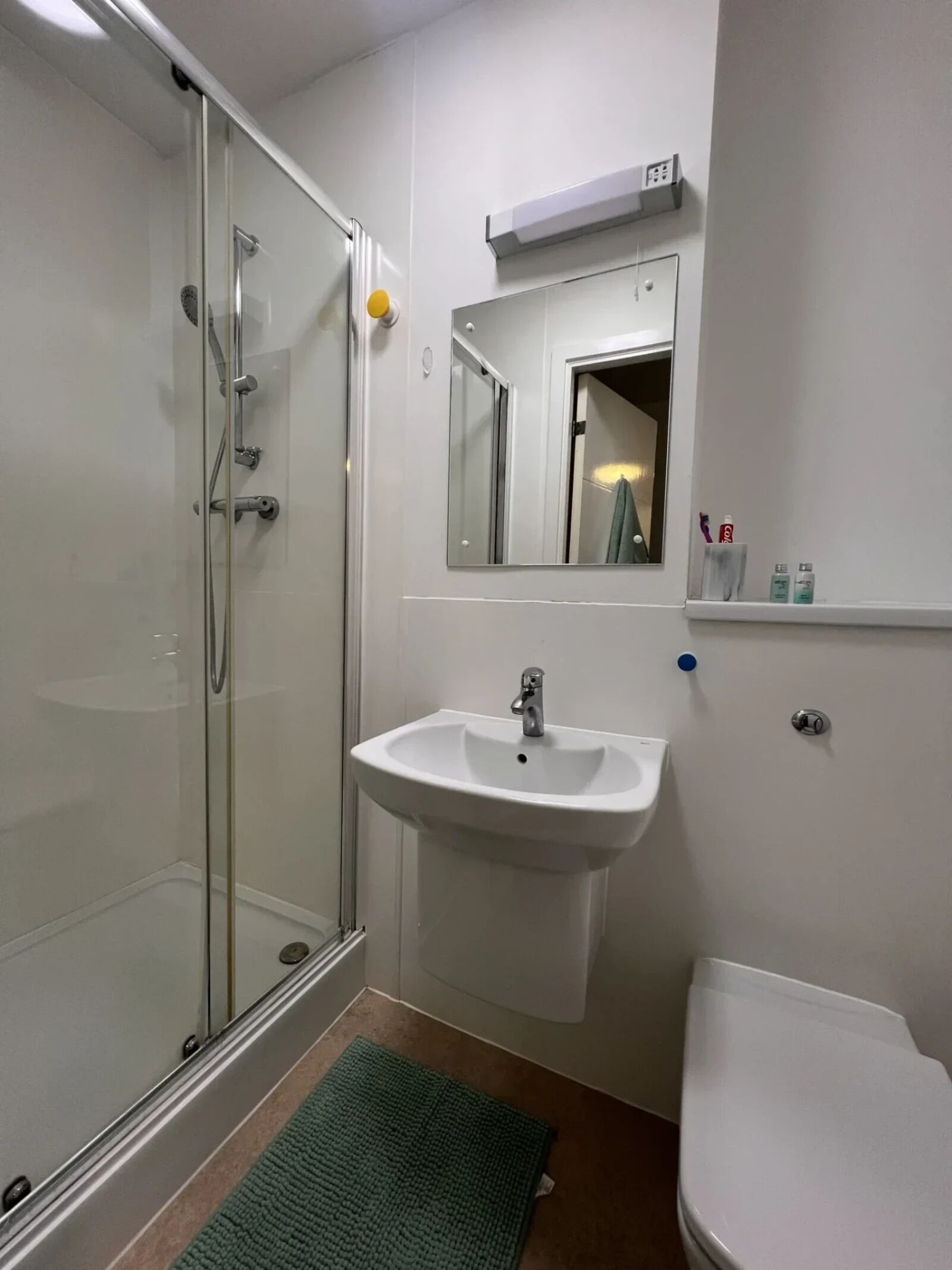 A bathroom with a glass-enclosed shower, a white sink, a toilet, and a mirror above the sink.