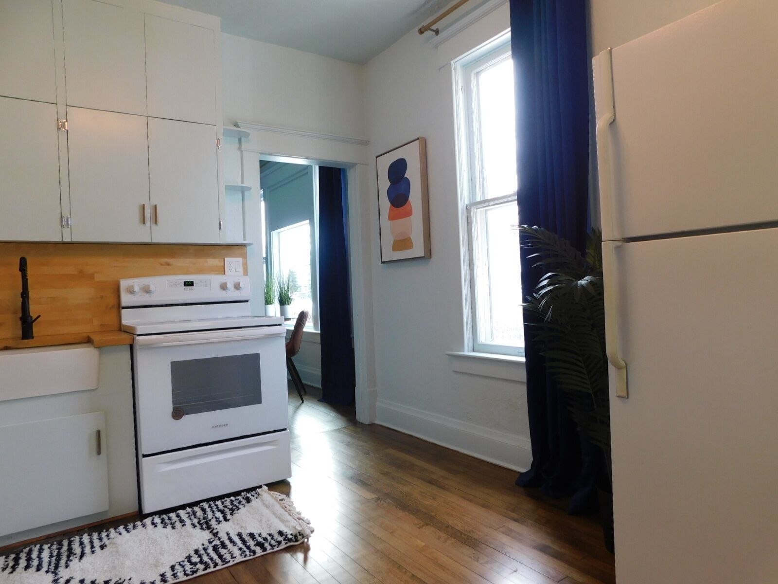 A kitchen with white cabinets, a white stove, and a refrigerator.