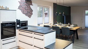 Una cocina moderna con horno integrado, cafetera y zona de comedor con mesa y sillas.