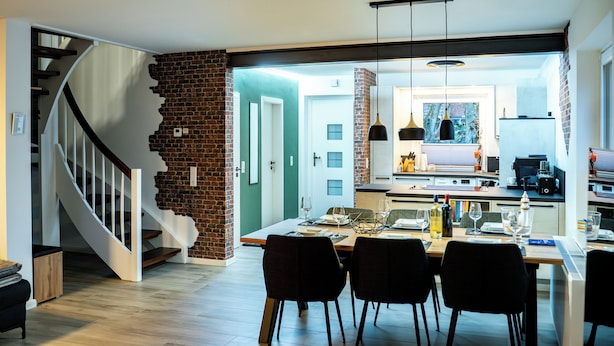 Una cocina moderna con comedor, una escalera y vista al salón.
