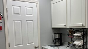 Una cocina con armarios blancos, encimera de mármol y cafetera.