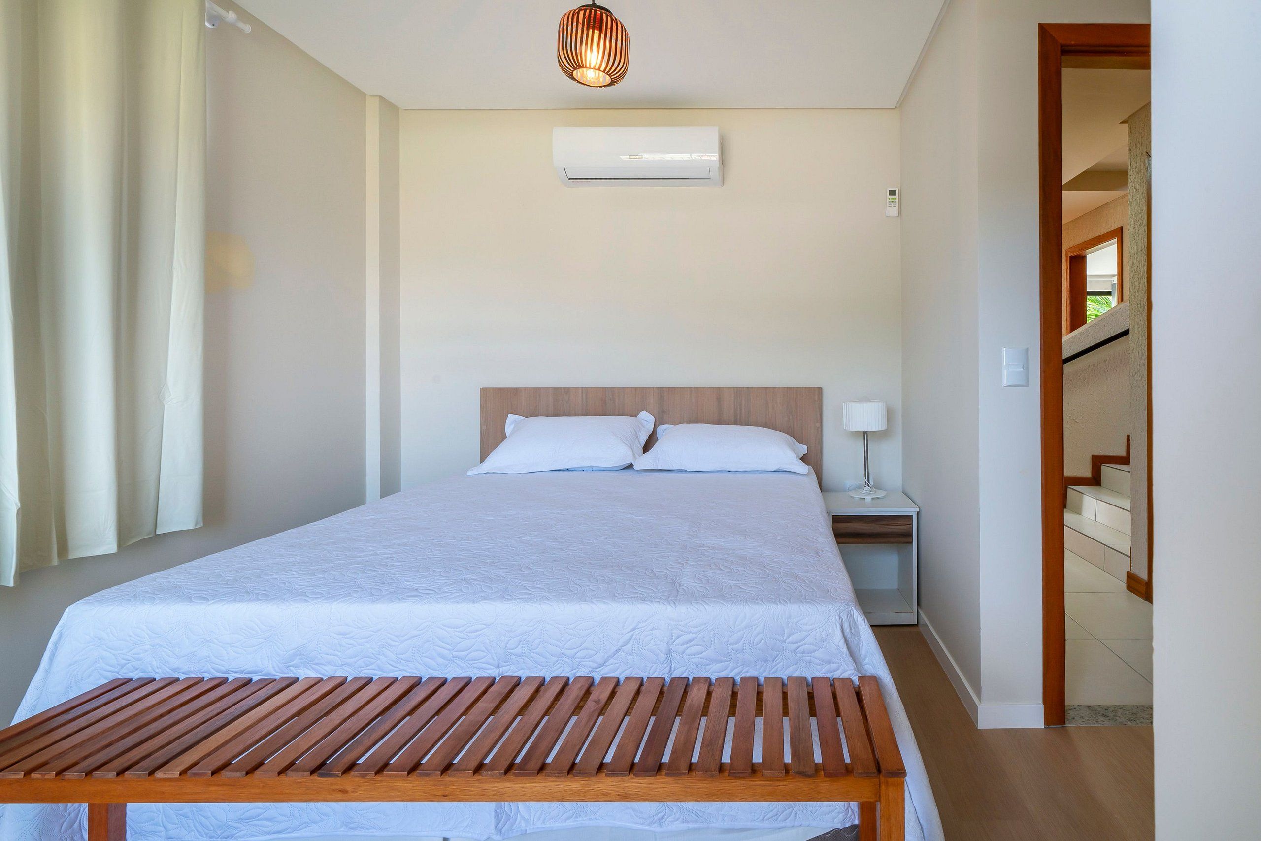 Un dormitorio con cama, mesita de noche, lámpara y un equipo de aire acondicionado.