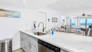 Una cocina moderna con lavavajillas, pileta de acero inoxidable y muebles blancos.