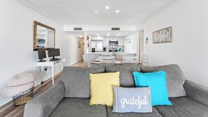 Una sala de estar moderna con un sofá gris, una mesa de comedor y una cocina al fondo.
