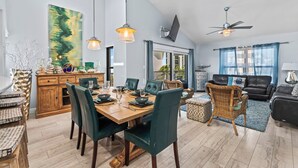 A spacious living area with a dining table, chairs, a sofa, and a ceiling fan. - Stay Beachside I Stunning Views Walk Everywhere (Clearwater Beach)