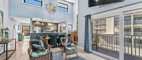 A spacious living room with a large TV, dining area, and kitchen.