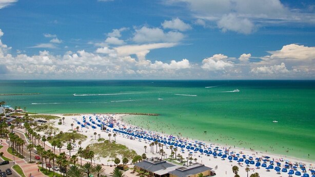 A beach with rows of blue umbrellas, a clear blue sky, and calm ocean waters. - Stay Beachside I Stunning Views Walk Everywhere (Clearwater Beach)