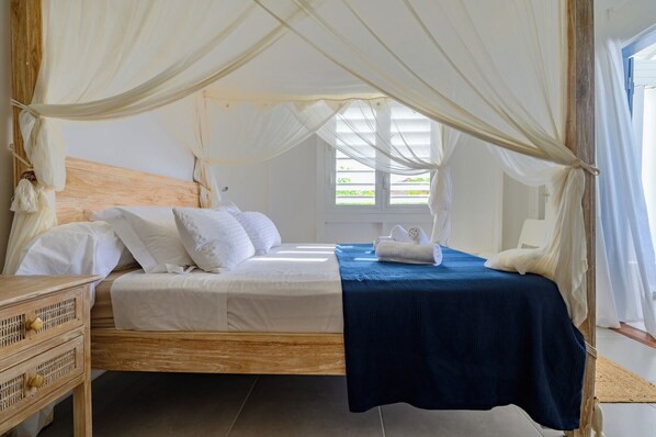 A bed with a wooden headboard, white bedding, a blue bedspread, and a canopy.
