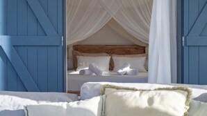 A bedroom with a canopy bed, white linens, and blue wooden walls. - Villa Paruline with swimming pool tropical garden and sea view (Grand-Bourg)