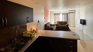 A modern kitchen with a central island, dark cabinets, and a built-in sink. - Bula Bliss (Nadi)
