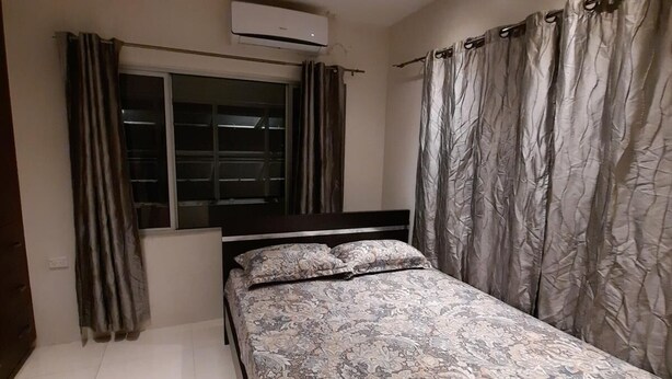 Quarto com cama, cortinas, aparelho de ar condicionado e janela.