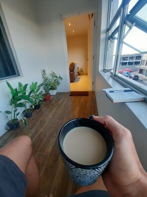 A view from a balcony with a coffee cup, potted plants, and a glimpse of a room with a bed and a chair. - Bula Bliss (Nadi)