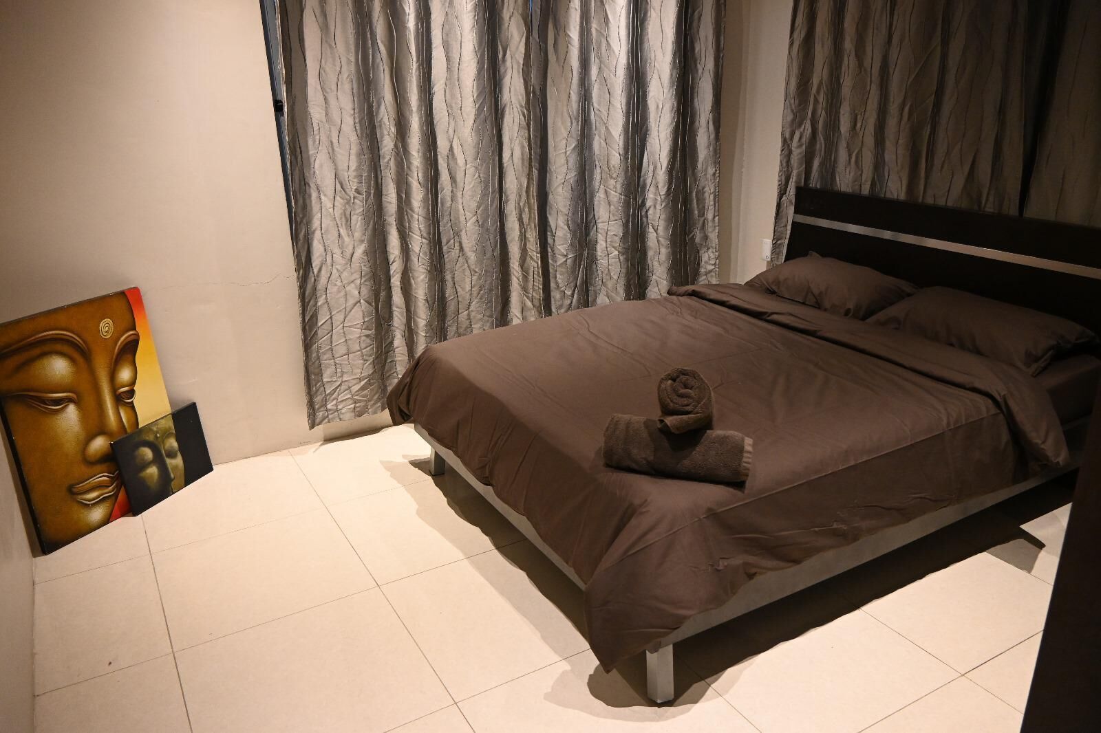 A bedroom with a bed, curtains, and a painting on the wall.