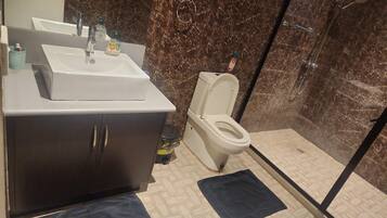 A bathroom with a white sink, dark cabinets, a toilet, and a shower area.