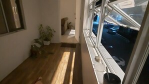 A room with a large window, a wooden floor, a plant, and a small table with a cup. - Bula Bliss (Nadi)
