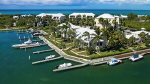 Ein Luftbild eines Resorts mit mehreren Gebäuden, einer Marina mit Booten und freiem Blick auf den Ozean.